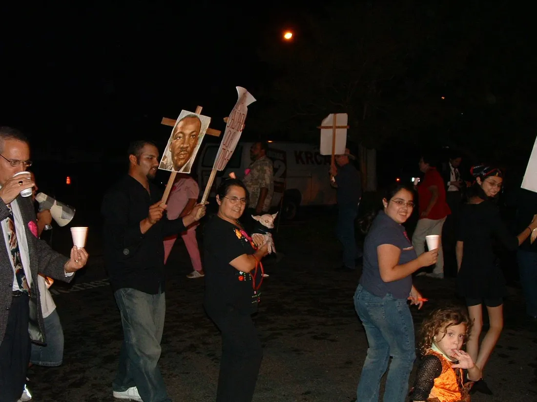 A candlelight march at night with members carrying signs and portraits