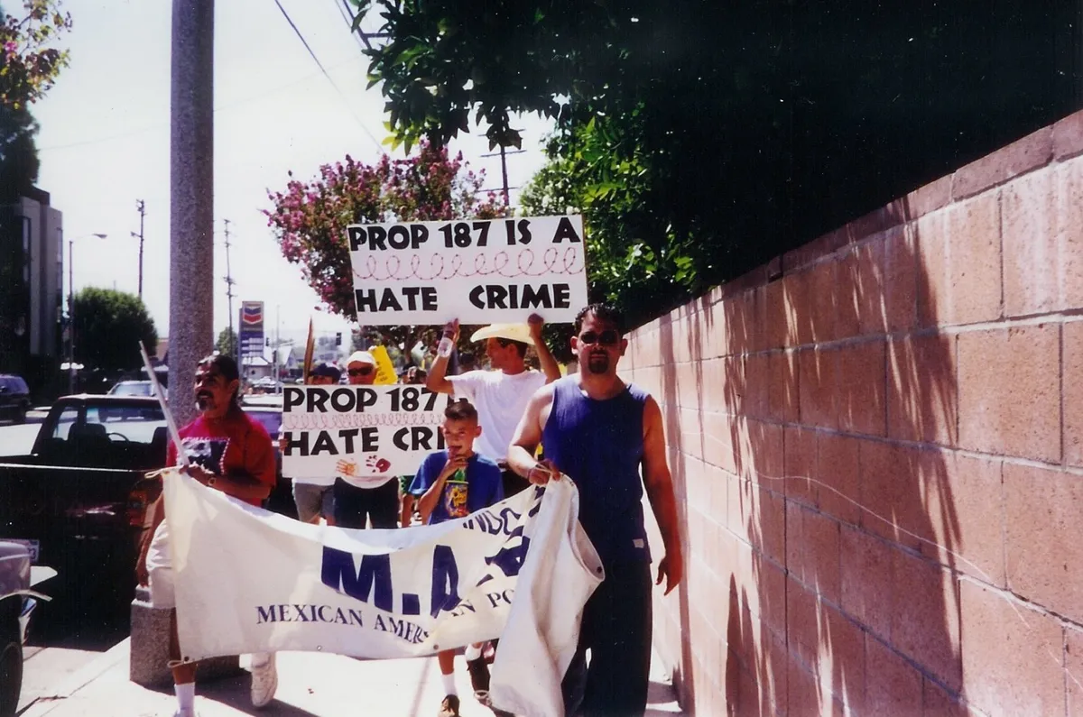 Marchers carrying a Mexican American Political Association banner and signs reading “Prop 187 is a hate crime”