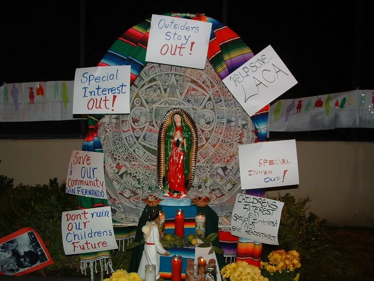 A community altar with the Virgin of Guadalupe and protest signs reading “Special Interest Out!” and “Save Our Community San Fernando”